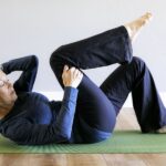 A woman laying on a green yoga mat