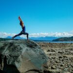 Fiji McAlpine yoga pose on large rock on beach