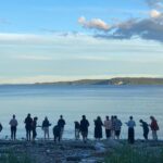 group of people standing at the waters edge