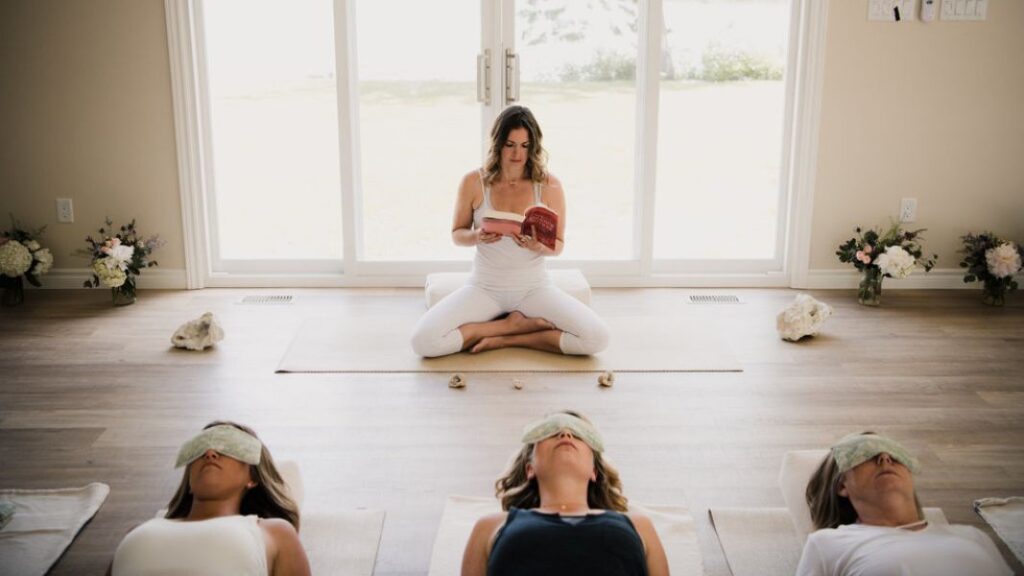 a woman in lotus position reading to a class