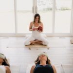 a woman in lotus position reading to a class