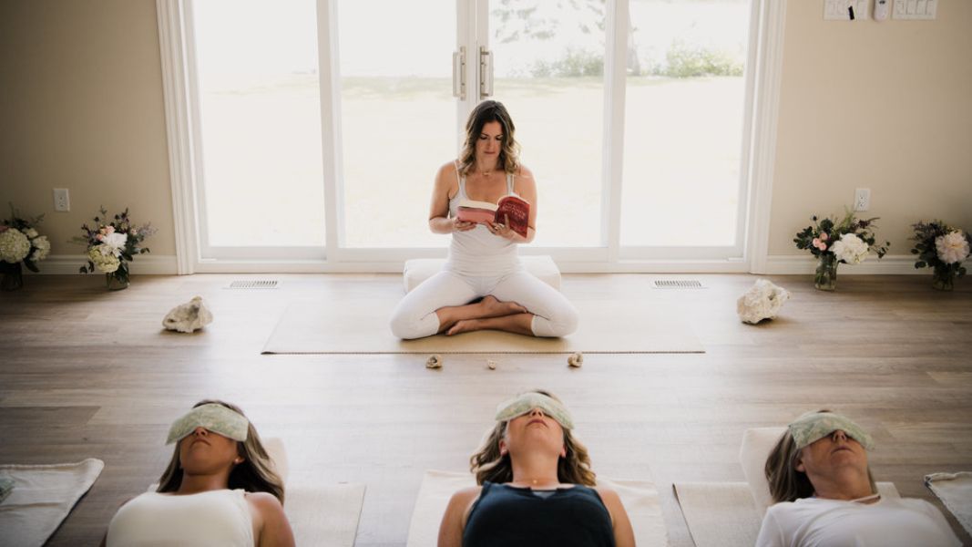 a woman in lotus position reading to a class